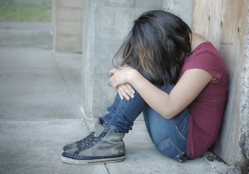 girl sitting against the wall crying