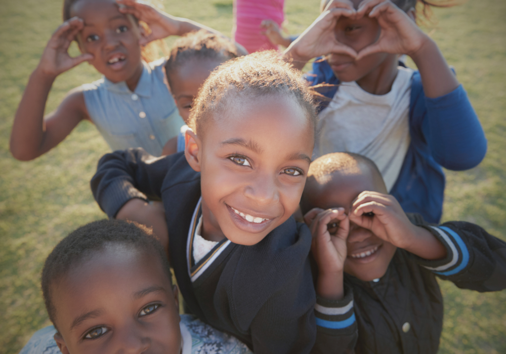 group of young kids smiling outside on a nice day